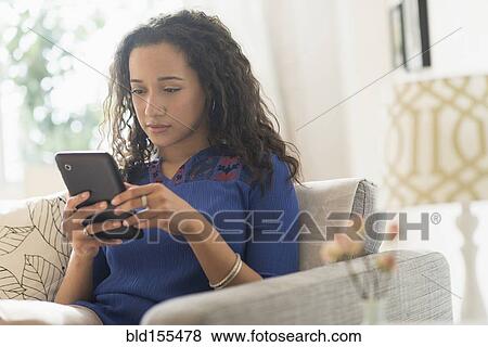 Mixed race woman using digital tablet on sofa View Large Photo Image Stock Photo - Mixed race woman using digital tablet on sofa. Fotosearch