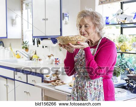 Stock Photograph - Older Caucasian woman baking pie in kitchen. Fotosearch