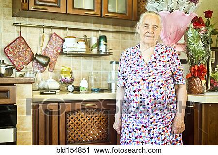 Stock Image - Older Caucasian woman standing in kitchen. Fotosearch