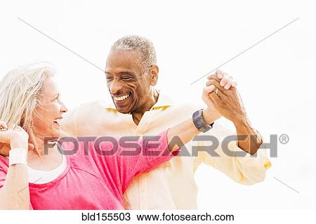 Stock Image - Older couple dancing on beach. Fotosearch