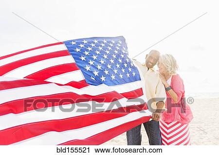 Older couple holding American flag on beach View Large Photo Image Stock Image - Older couple holding American flag on beach. Fotosearch
