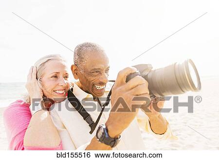 Older couple photographing on beach View Large Photo Image Stock Photograph - Older couple photographing on beach. Fotosearch