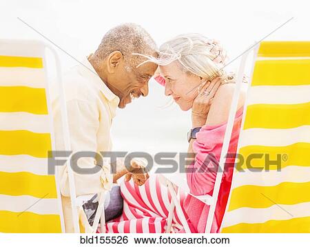Older couple sitting in lawn chairs on beach View Large Photo Image Stock Photograph - Older couple sitting in lawn chairs on beach. Fotosearch