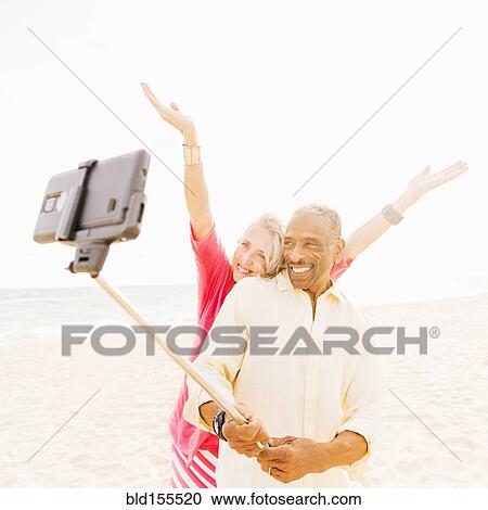 Older couple taking cell phone photograph on beach View Large Photo Image Stock Image - Older couple taking cell phone photograph on beach. Fotosearch