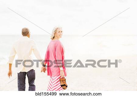 Stock Photo - Older couple walking on beach. Fotosearch