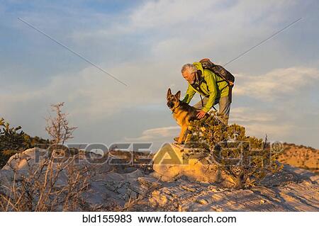 Stock Image - Older man and dog on remote rock formations. Fotosearch