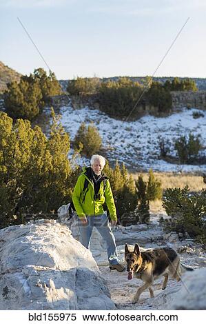 Stock Photography - Older man and dog standing on remote rock formations. Fotosearch