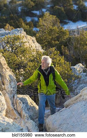 Stock Image - Older man climbing remote rock formations. Fotosearch