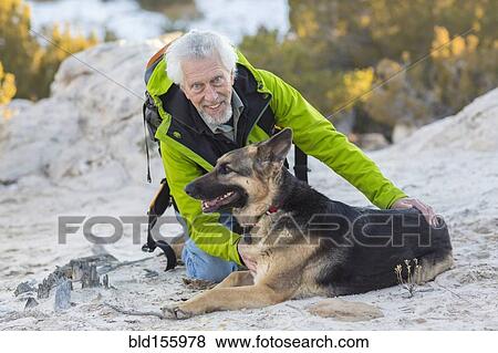 Older man petting dog on rocky hillside View Large Photo Image Stock Photo - Older man petting dog on rocky hillside. Fotosearch