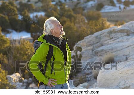 Stock Image - Older man standing on remote rock formations. Fotosearch
