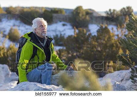 Stock Photo - Older man standing on rock formations. Fotosearch