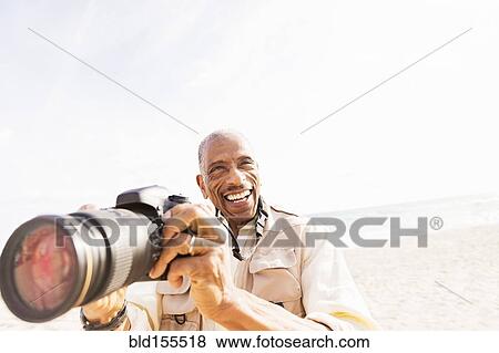 Older mixed race man photographing on beach View Large Photo Image Stock Photo - Older mixed race man photographing on beach. Fotosearch