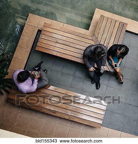 Stock Image - Overhead view of business people sitting in office courtyard. Fotosearch