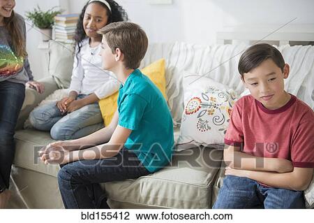 Pouting boy ignoring friends in living room View Large Photo Image Stock Image - Pouting boy ignoring friends in living room. Fotosearch