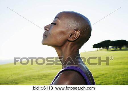 Stock Image - Profile of African American woman smiling in park. Fotosearch