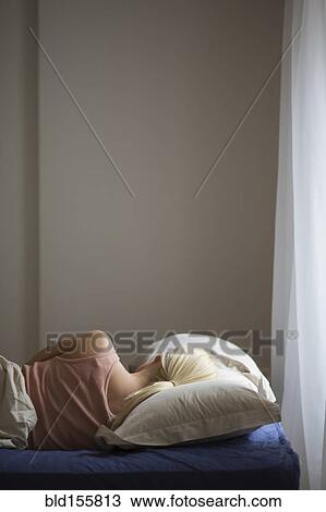 Stock Image - Rear view of woman sleeping in bed. Fotosearch