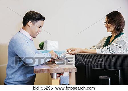 Secretary offering tablet to businessman in office lobby View Large Photo Image Stock Photography - Secretary offering tablet to businessman in office lobby. Fotosearch