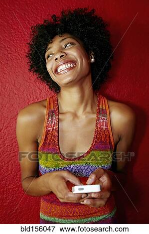 Stock Photo - Smiling black woman using cell phone. Fotosearch