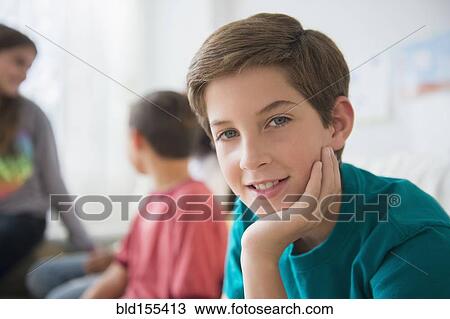 Smiling boy resting chin in hand in living room View Large Photo Image Stock Image - Smiling boy resting chin in hand in living room. Fotosearch