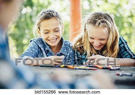Stock Photograph - Smiling Caucasian girls coloring outdoors. Fotosearch