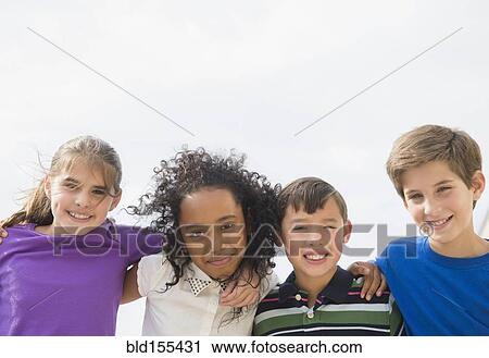 Stock Image - Smiling children hugging outdoors. Fotosearch