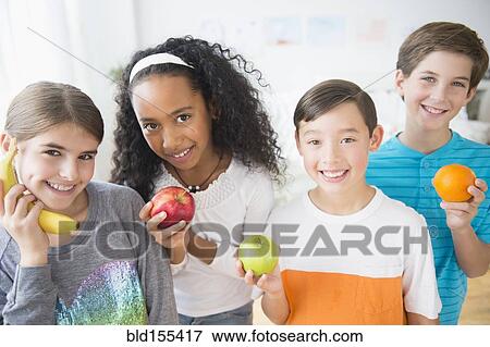 Smiling children playing with healthy fruit View Large Photo Image Stock Photo - Smiling children playing with healthy fruit. Fotosearch
