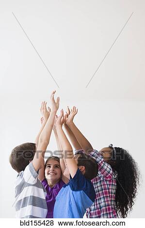 Stock Photo - Smiling children raising hands in center . Fotosearch