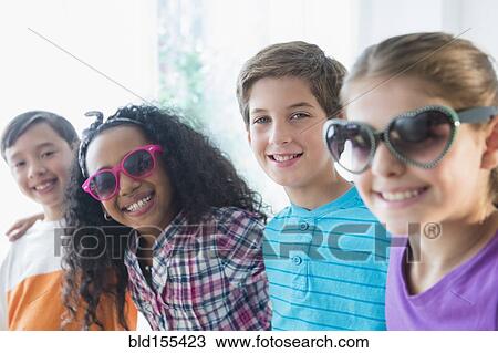 Stock Image - Smiling friends wearing sunglasses. Fotosearch