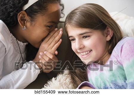 Smiling girls whispering on sofa View Large Photo Image Stock Photo - Smiling girls whispering on sofa. Fotosearch