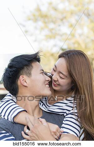 Stock Photograph - Smiling Korean couple hugging outdoors. Fotosearch