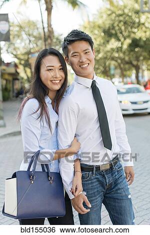 Stock Photograph - Smiling Korean couple standing in street. Fotosearch