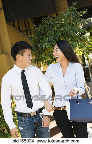 Picture - Smiling Korean couple walking on sidewalk. Fotosearch