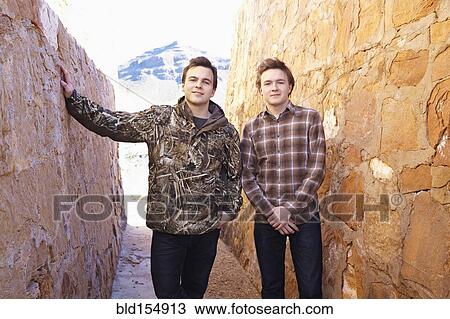 Smiling men standing between rock walls View Large Photo Image Stock Image - Smiling men standing between rock walls. Fotosearch