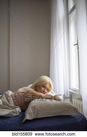 Stock Photo - Smiling woman laying in bed. Fotosearch