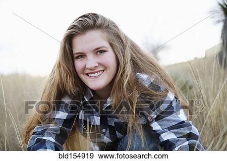 Stock Photo - Smiling woman sitting in tall grass. Fotosearch