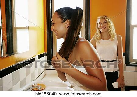 Smiling women holding hair in bathroom mirror View Large Photo Image Stock Image - Smiling women holding hair in bathroom mirror. Fotosearch