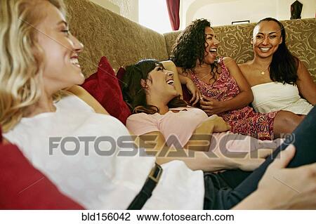 Smiling women laughing on sofa View Large Photo Image Stock Image - Smiling women laughing on sofa. Fotosearch