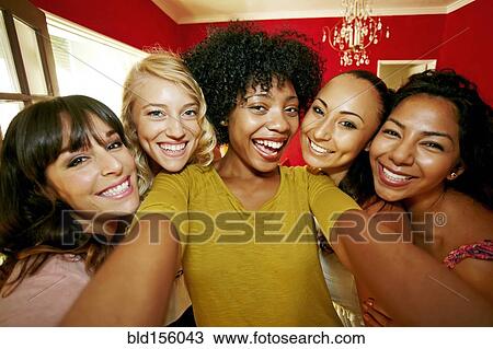 Stock Image - Smiling women taking photograph together. Fotosearch