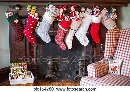 Stock Image - Stuffed Christmas stockings over fireplace. Fotosearch