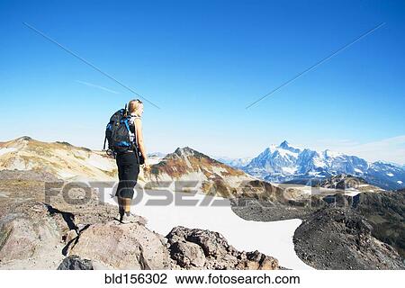 Stock Image - Woman admiring mountains in remote landscape. Fotosearch