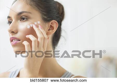 Stock Photo - Woman applying moisturizer to cheek. Fotosearch