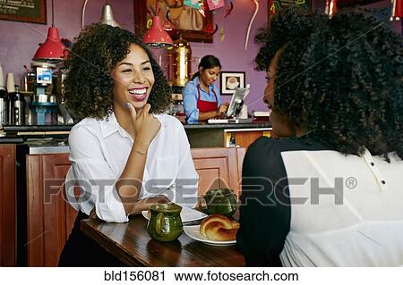 Stock Image - Women drinking coffee and talking in cafe. Fotosearch