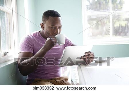 Black man drinking coffee and using digital tablet View Large Photo Image Stock Image - Black man drinking coffee and using digital tablet. Fotosearch