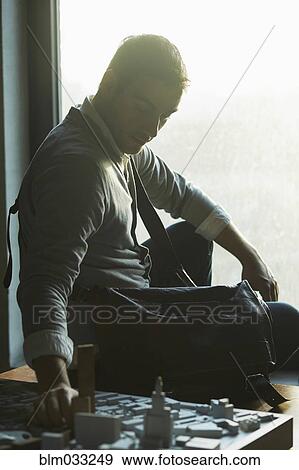 Caucasian architect at office window examining urban model View Large Photo Image Stock Photo - Caucasian architect at office window examining urban model. Fotosearch