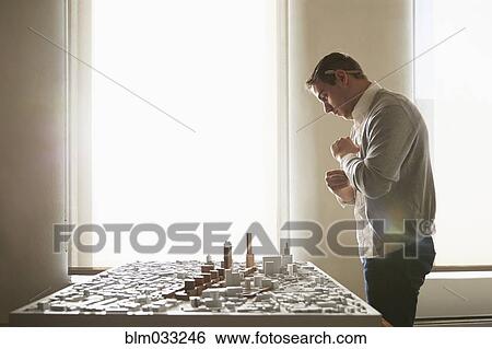 Stock Photograph - Caucasian architect examining urban model in office. Fotosearch