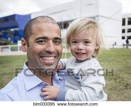 Stock Photography - Hispanic father and son smiling in field. Fotosearch