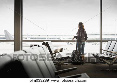 Stock Photo - Hispanic woman looking out airport window. Fotosearch