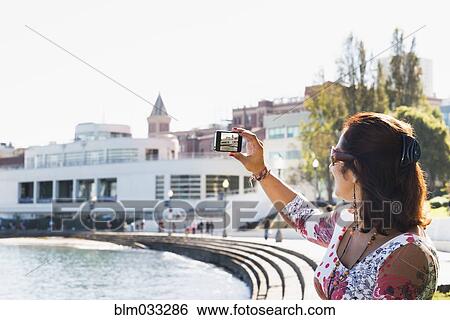 Hispanic woman taking cell phone photograph of waterfront View Large Photo Image Stock Photograph - Hispanic woman taking cell phone photograph of waterfront. Fotosearch