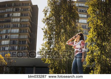 Hispanic woman talking on cell phone near trees View Large Photo Image Stock Photo - Hispanic woman talking on cell phone near trees. Fotosearch