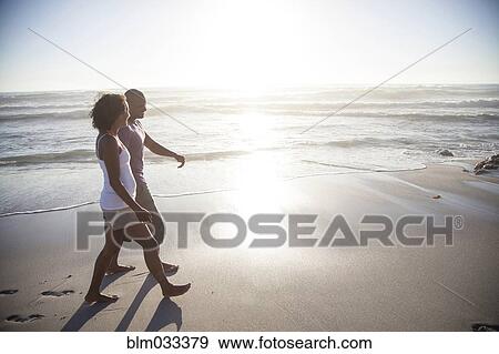 Stock Photo - Mixed race couple walking on beach. Fotosearch